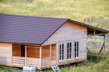 Wall Mural - wooden house made of timber and planks with a roof made of metal. House among the steppe.