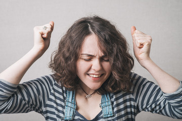 happy girl with fists, dressed in overalls