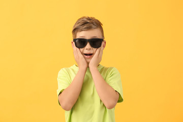 Wall Mural - Surprised little boy with sunglasses on color background