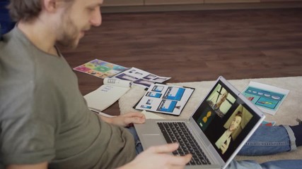 Wall Mural - tilt up side view shot of young marketing specialist having video call with two colleagues on laptop