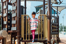 Girl Playing On Playground Equipment In Park
