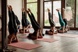 © Javier Pardina/Stocksy - Scene of a group of people practicing yoga in class.