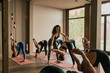 © Javier Pardina/Stocksy - Scene of a group of people practicing yoga in class.