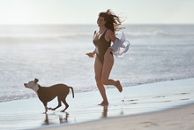 Woman Running With Dog On Beach