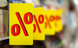 © 8th - Sign of '%' wording at consumer good's shelf in the supermarket.  '%' label (tag), symbol of special promotion as concept of offering product at reduced price. Shelves in blurry for background.