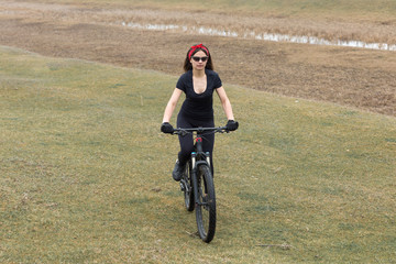 Girl on a mountain bike on offroad, beautiful portrait of a cyclist in rainy weather, Fitness girl rides a modern carbon fiber mountain bike in sportswear. Close-up portrait of a girl in red bandana.