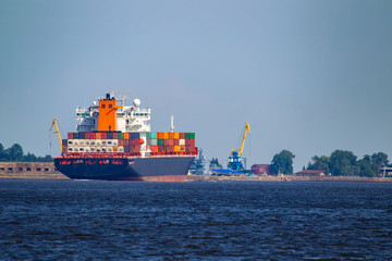 Cargo ships sailing off the coast. Container ship near the cargo port. Container ship on the background of blue sky. Shipping. Concept - Transfer of goods by water. Containers loaded on a sea vessel