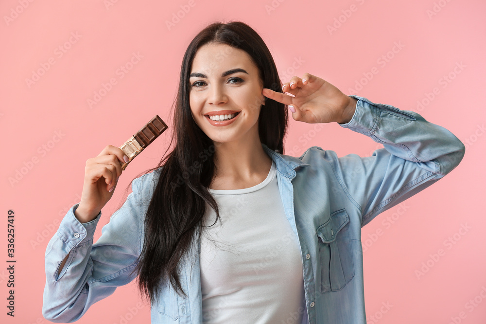 Beautiful young woman with chocolate on color background