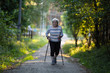 © De Visu - An elderly woman with ski poles is on the road. Nordic walking.