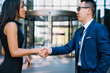 © BullRun - Confident Hispanic lady shaking hands making deal with partner