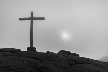 Large concrete cross on top of the peak of Bandeira, with sun between the clouds in the background, Alto do Caparao, Minas Gerais, Brazil