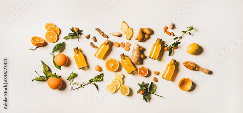 Immune boosting natural vitamin health defending drink to resist virus. Flat-lay of fresh turmeric, ginger and citrus juice shots over white background, top view. Vegan Immunity system booster