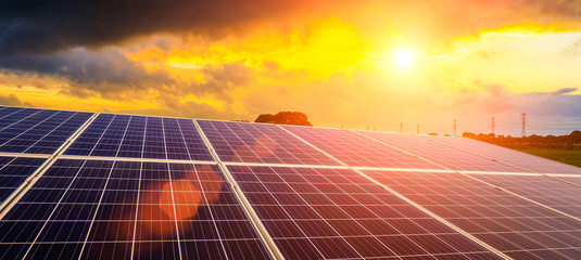 photovoltaic solar panels and high voltage power lines at sunset sky background,green clean alternat