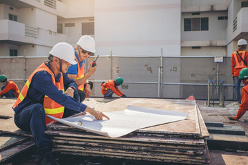 Structural engineer and architect working with blueprints discuss at the outdoors construction site.