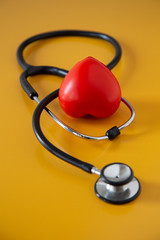 Stethoscope doctors and red heart cardiology placed on a Yellow table in the hospital,