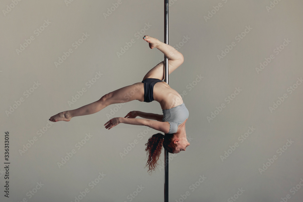 Beautiful sports girl doing acrobatics on a pole - obrazy, fototapety, plakaty 