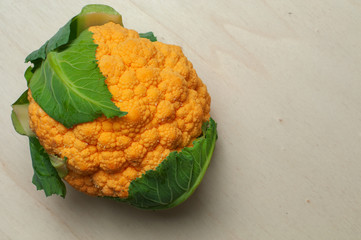 head of an orange cauliflower with green leaves