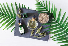 Green Bottles Of Medical CBD Oil With Cannabis Seeds And Dried Buds Top View On White Background. Alternative Medicine Concept.