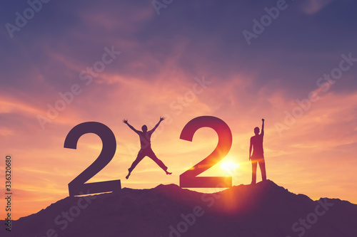 Cuadros en Lienzo Man raise hand up and man jumping on sunset sky at top of mountain and number like 2021 abstract background