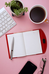 Blank notebook with pen are on top of white office desk table with computer tools and others