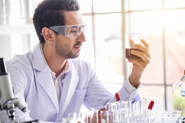 Wall Mural - attractive happiness scientist man lab technician assistant analyzing sample in test tube at laborat
