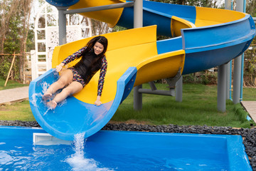 Asian girl on water slide at aquapark.