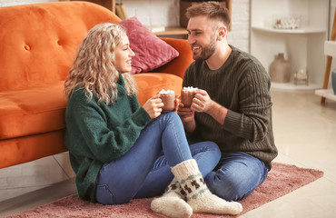 Wall Mural - Happy young couple drinking hot cocoa at home