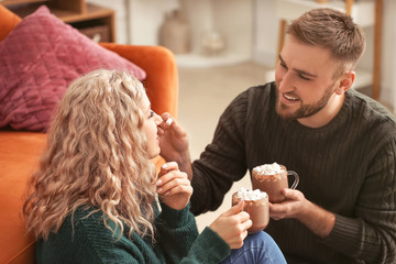 Poster - Happy young couple drinking hot cocoa at home