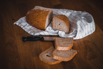 Rustic crusty loaves of bread on wooden plate. Bakery concept with cut sliced homemade bread. Sliced bread on a wooden cutting board.