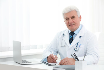 Wall Mural - Portrait of senior doctor in white coat at workplace