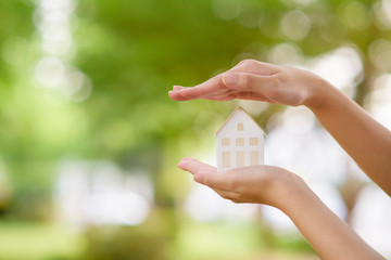 Close up woman hand is holding house on green background