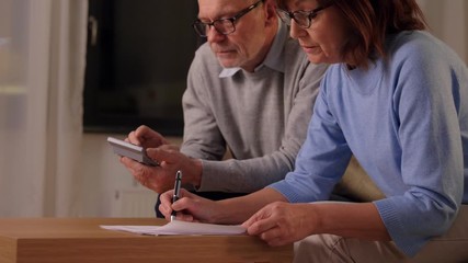 Sticker - family, savings and people concept - smiling senior couple with papers and calculator at home