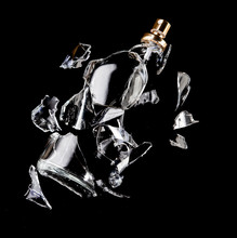 A Glass Perfume Bottle Shatters Into Fragments On A Black Background, The Isolated Texture Of Glass Container Fragments