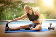 © goodluz - Woman doing fitness exercises outside by the pool