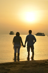 Canvas Print - Happy elderly couple holding hands at tropical beach at sunset