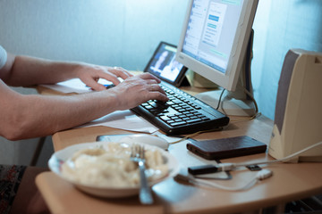 man typing on a keyboard at a computer desk, remote work at home