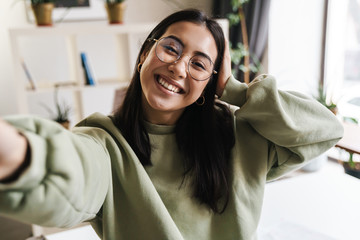 Wall Mural - Cheery optimistic young girl student indoors take a selfie