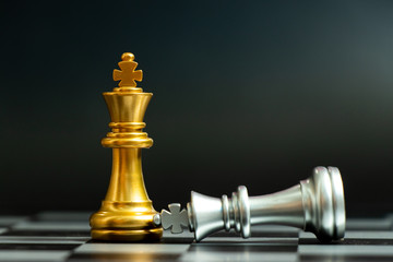 Wall Mural - Gold king chess piece win over lying down silver king on black background