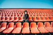 © Irina84 - Curly girl in a surgical mask sitting in an empty stadium during epidemic disease Covid-19.