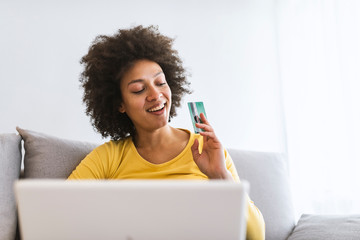 Wall Mural - Female consumer spending buying on internet, lifestyle. Happy woman shopping online with laptop at home. Woman using laptop computer shopping on line, using credit card playing online, smiling indoors