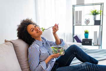 Wall Mural - Enjoying a healthy snack. Portrait of happy smiling young woman with vegetarian vegetable salad, indoors or at home. Beauty and dieting concept. Weight lossing, by healthy eating