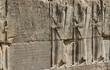 starożytne płaskorzeźby mężczyzn wykute w kamieniu na jednej ze ścian w persepolis w iranie