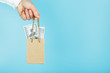 © Alexander - A small paper bag for financial aid and support made of paper at arm's length with US dollars on a blue background. The concept of negligible financial support in business,