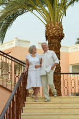 Canvas Print - Happy senior couple at hotel resort on steps