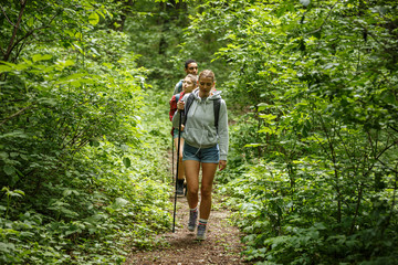 group of friends hiking in nature.they walking trough forest and meadows.blond hair female are in fo