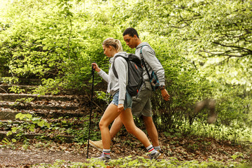Wall Mural - young couple hiking trough forest.they enjoying in walk and fresh air.