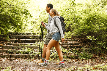 Wall Mural - young couple hiking trough forest.they enjoying in walk and fresh air.