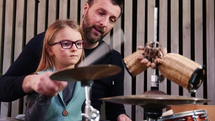 Wall Mural - Father and daughter play percussion together.Little girl learning drums with her dad at home.Front view.Percussion class at home