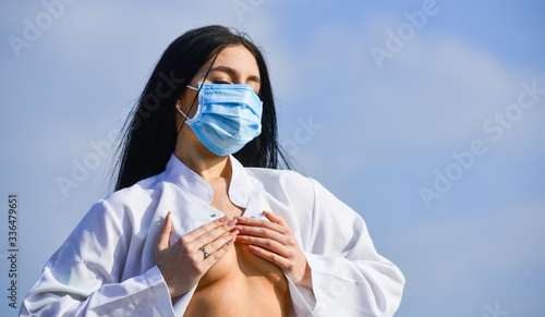 breast cancer concept. coronavirus pandemic outbreak. platic surgery. put silicone implant in boobs. medical care. sexy doctor. woman nurse in respirator mask cover bare breast. copy space