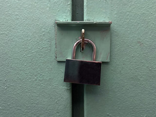 closed lock on the color door. old padlock on the door. green metal door with padlock, texture and background